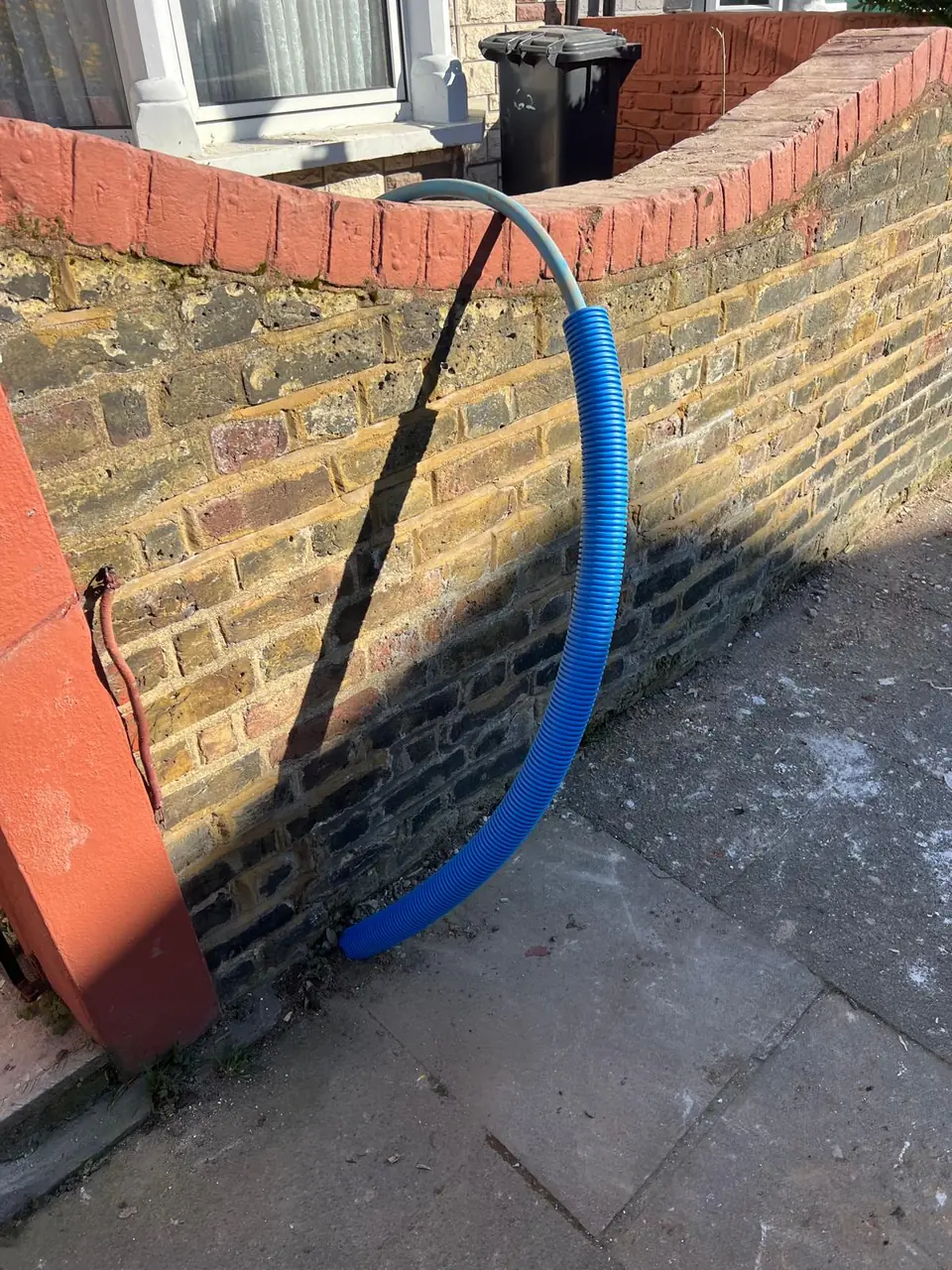 Blue protective pipe duct brought to a property wall