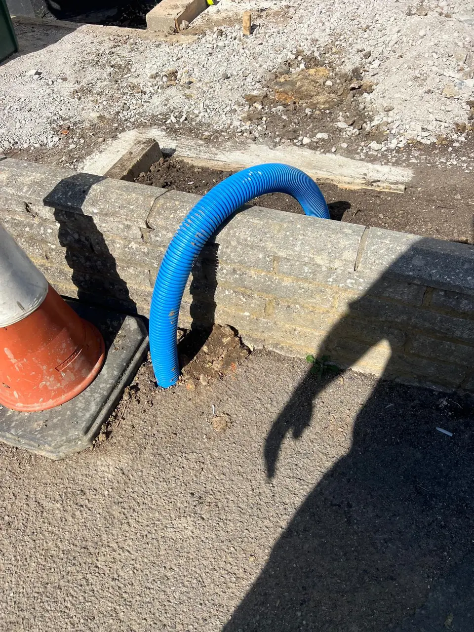 Blue protective duct emerging from a compact paved access point