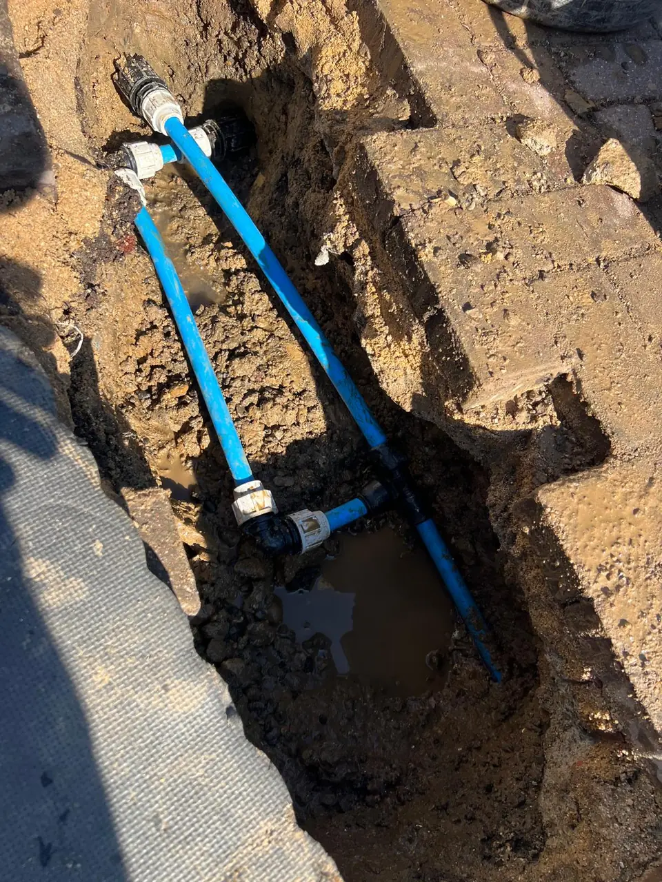 Two blue water supplies connected below ground