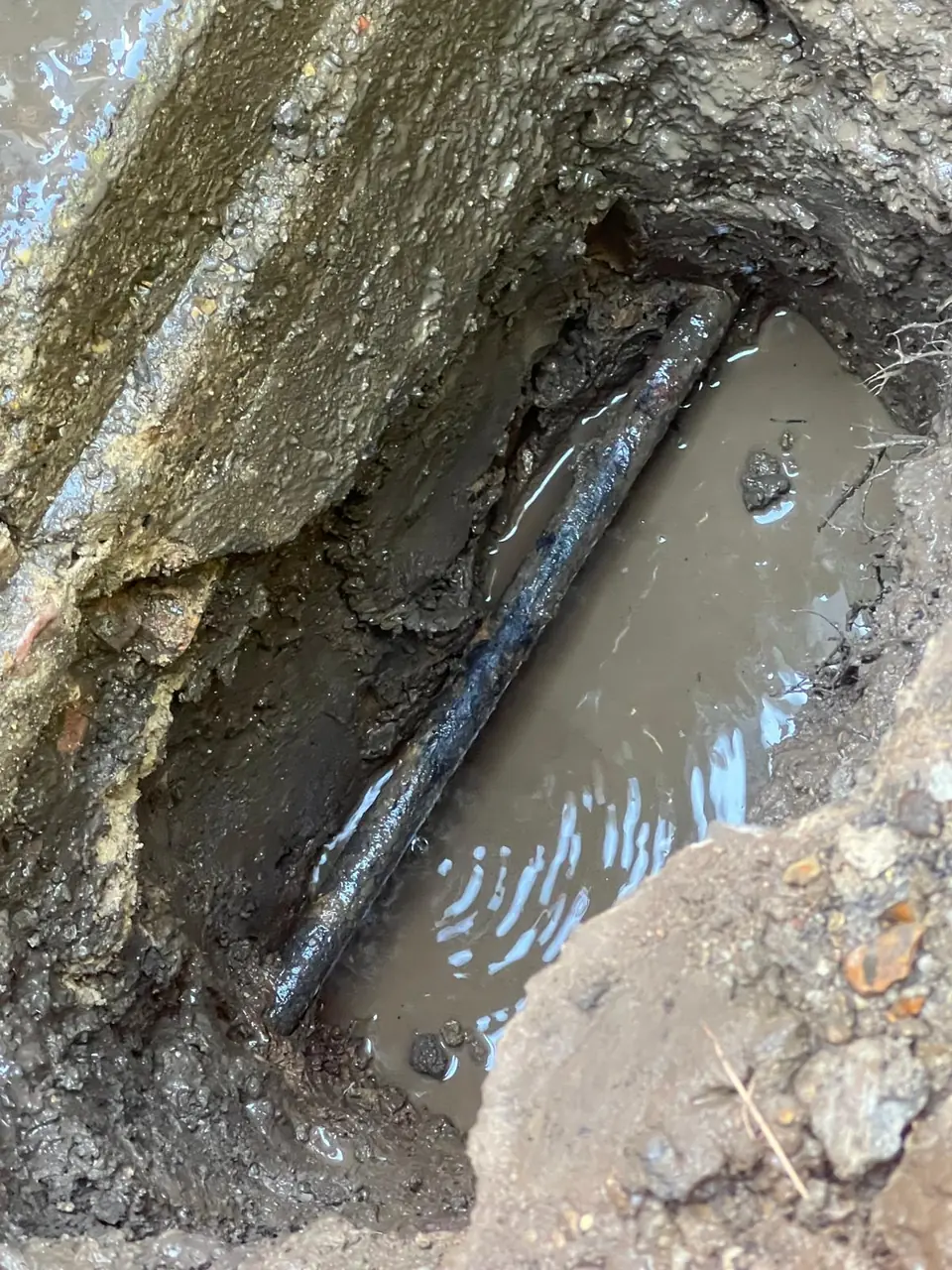 Existing buried pipe exposed in a waterlogged trench