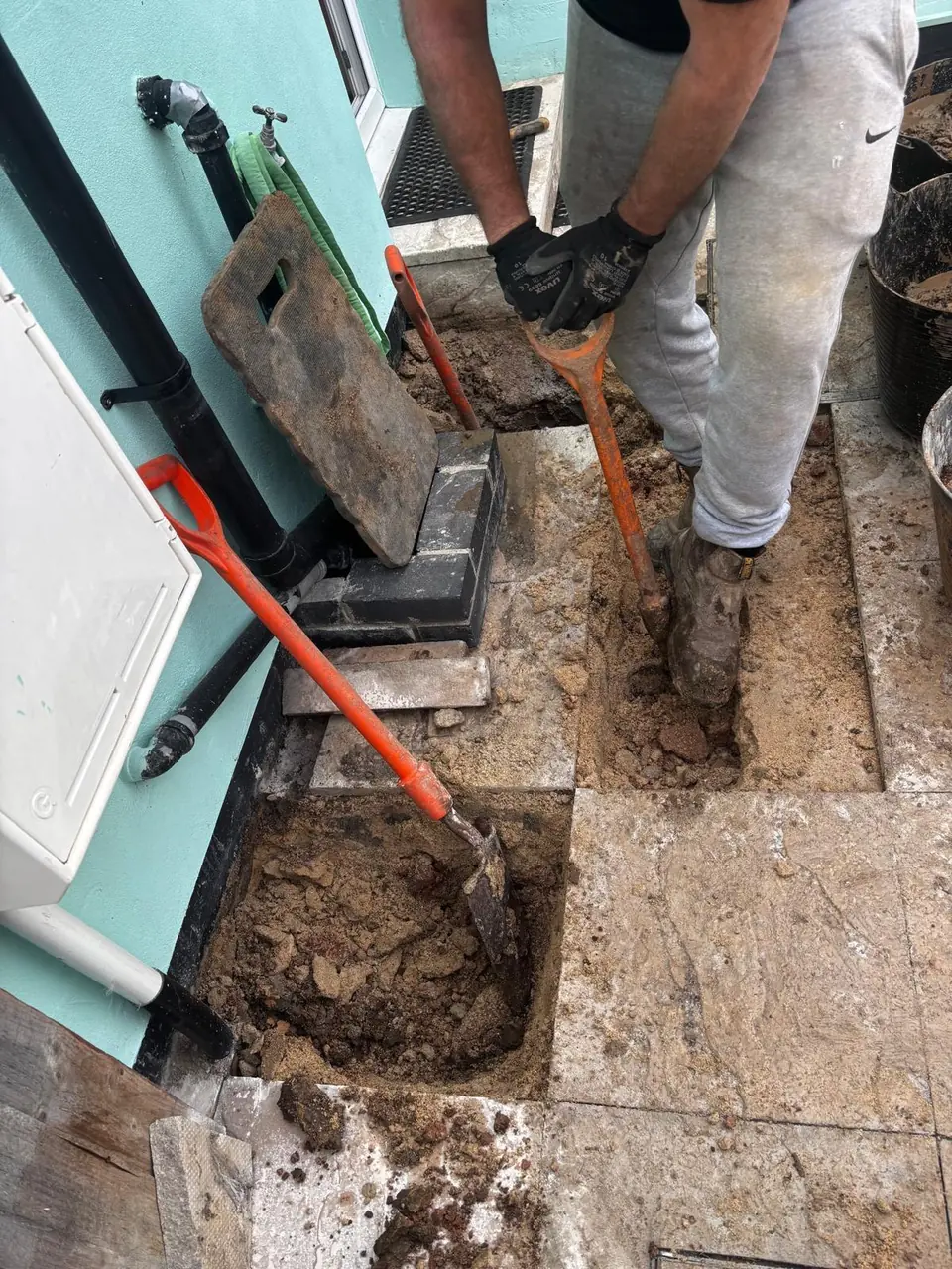 Narrow underground pipe route excavated beside a property