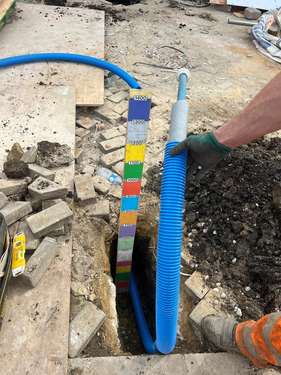 Blue protective duct being installed below ground