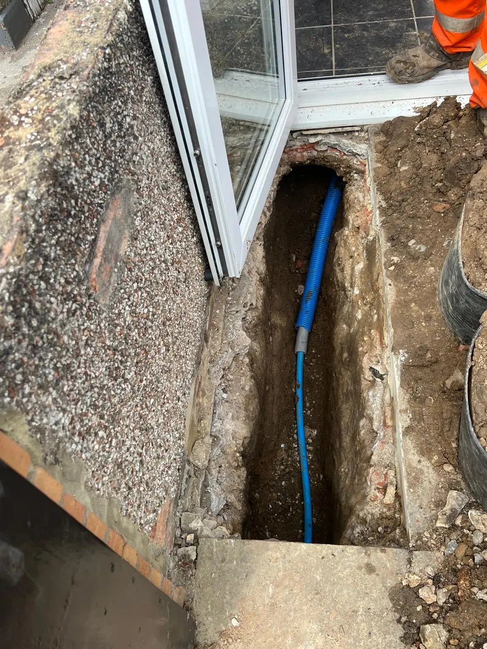 Blue water supply pipe being routed alongside a brick property